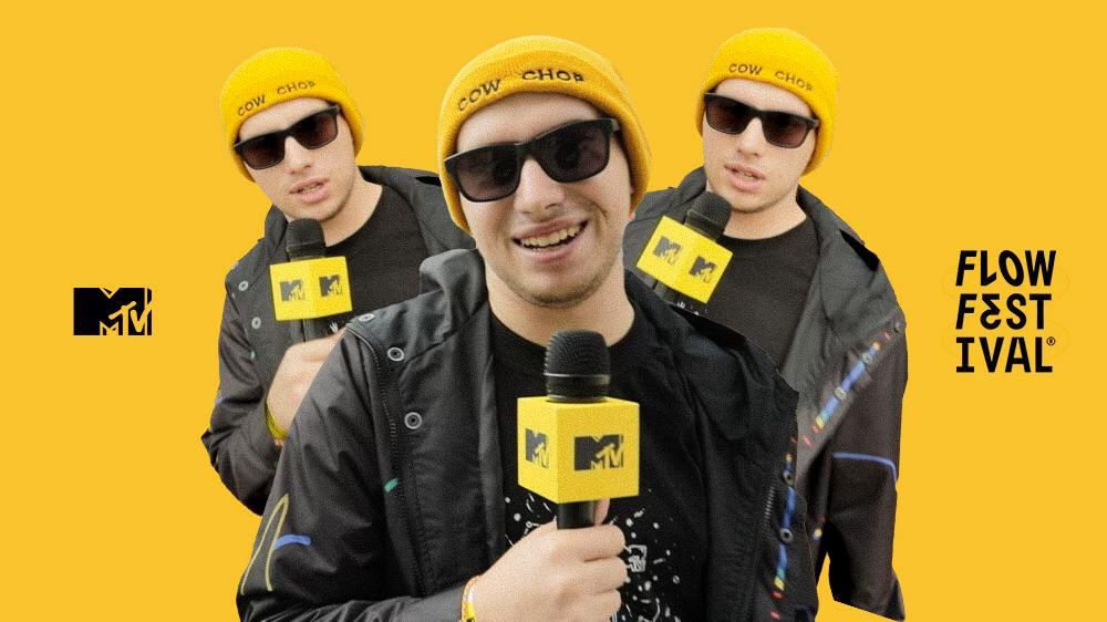 Andrey Korolev at Flow Festival, holding an MTV microphone while wearing a yellow 'Cow Chop' beanie and sunglasses, with a vibrant yellow background featuring MTV and Flow Festival logos.