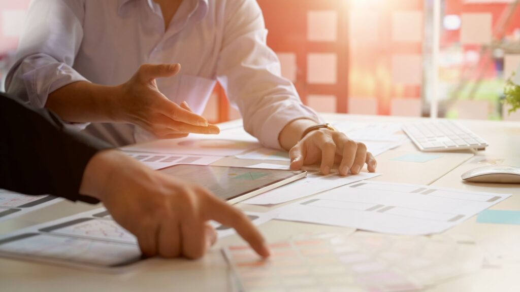 image of people pointing at plans on a desk planning for a project